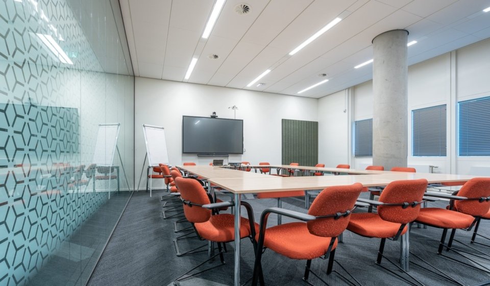 The conference room interior of a modern office with white walls and a monitor